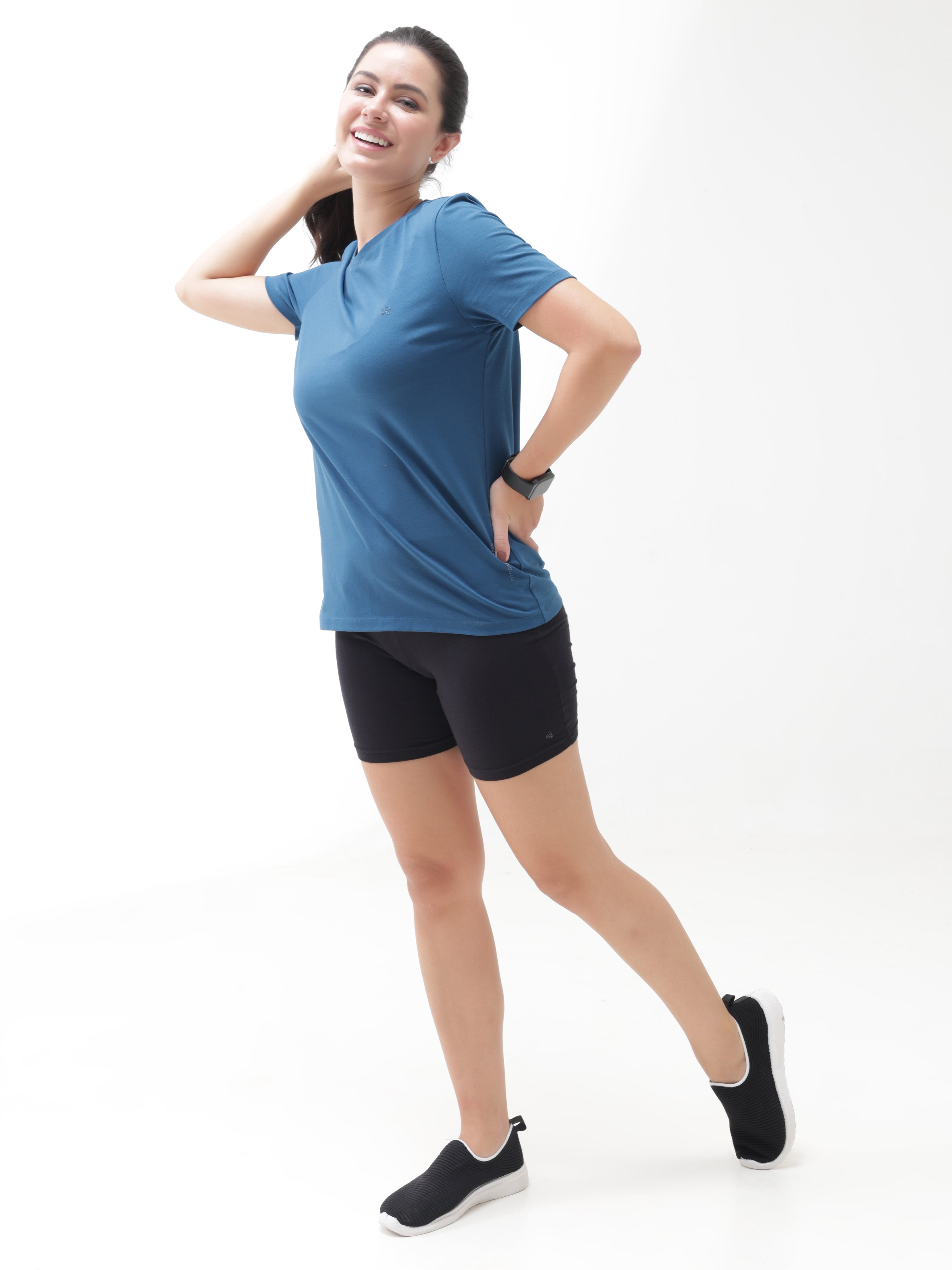 Woman wearing a blue Turms anti-stain, anti-odour, stretchable T-shirt in a tailored fit with round neck, showcased in a dynamic pose.