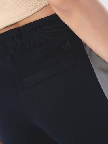 Close-up of a woman's joggers featuring a black fabric, elastic waistband, and stylish pocket detail.