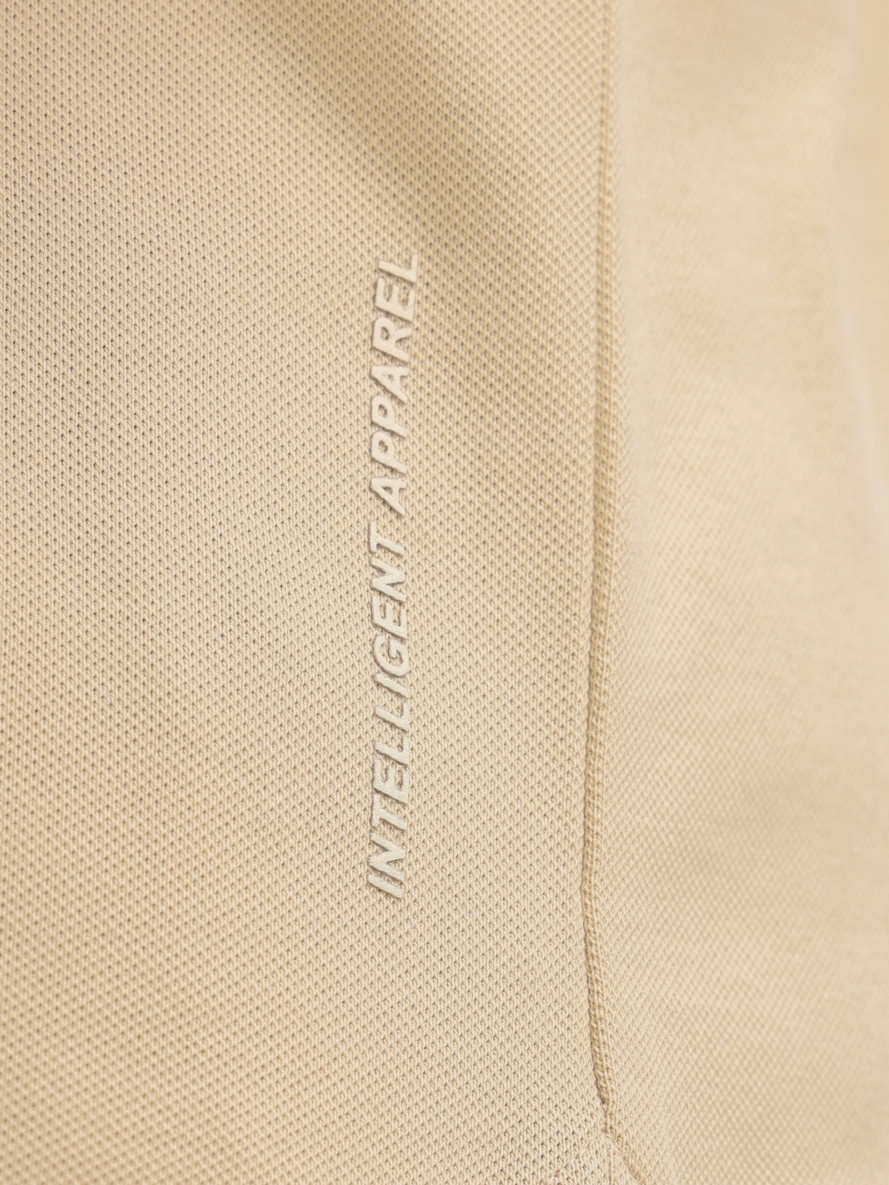 Close-up of textured fabric with "Intelligent Apparel" text on premium cotton-spandex blend Sandstone Polo T-shirt for men.