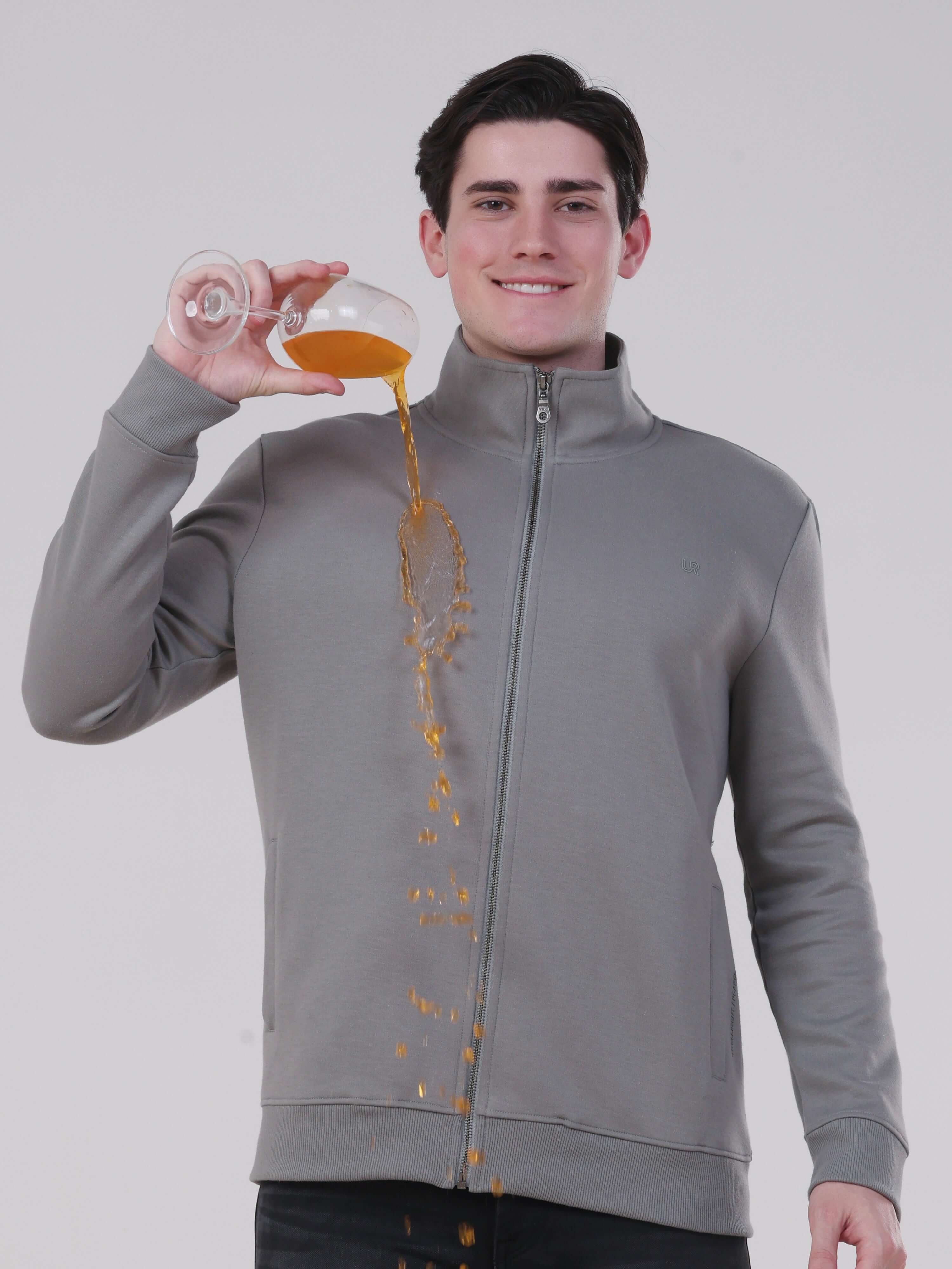 Man wearing Turms Intelligent Traveller Jacket, showcasing its anti-stain feature while pouring liquid.