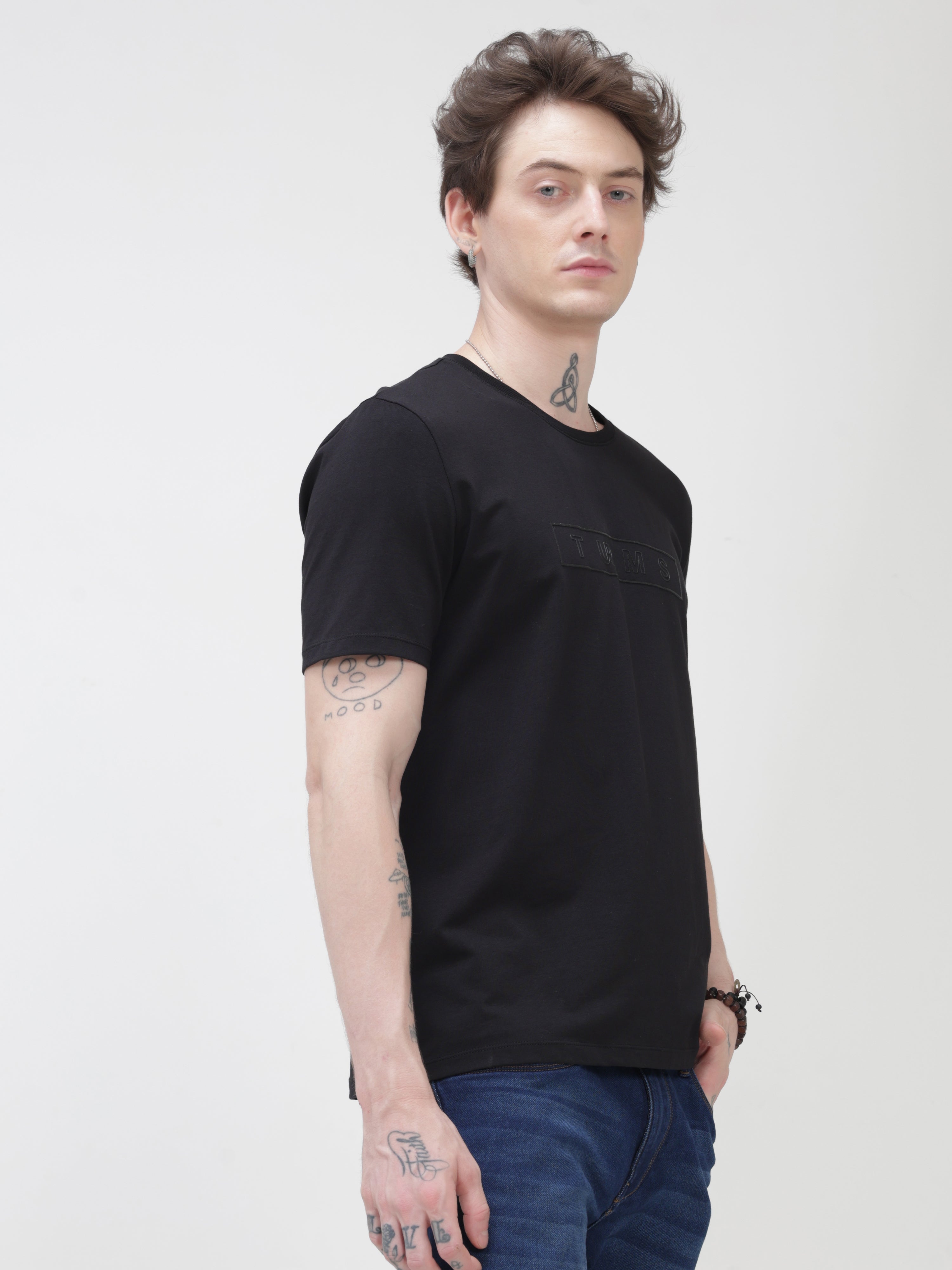 Man wearing Midnight Elegance Turms T-shirt, anti-stain and anti-odor, black round-neck, tailored fit, premium cotton blend, stylish casual wear.