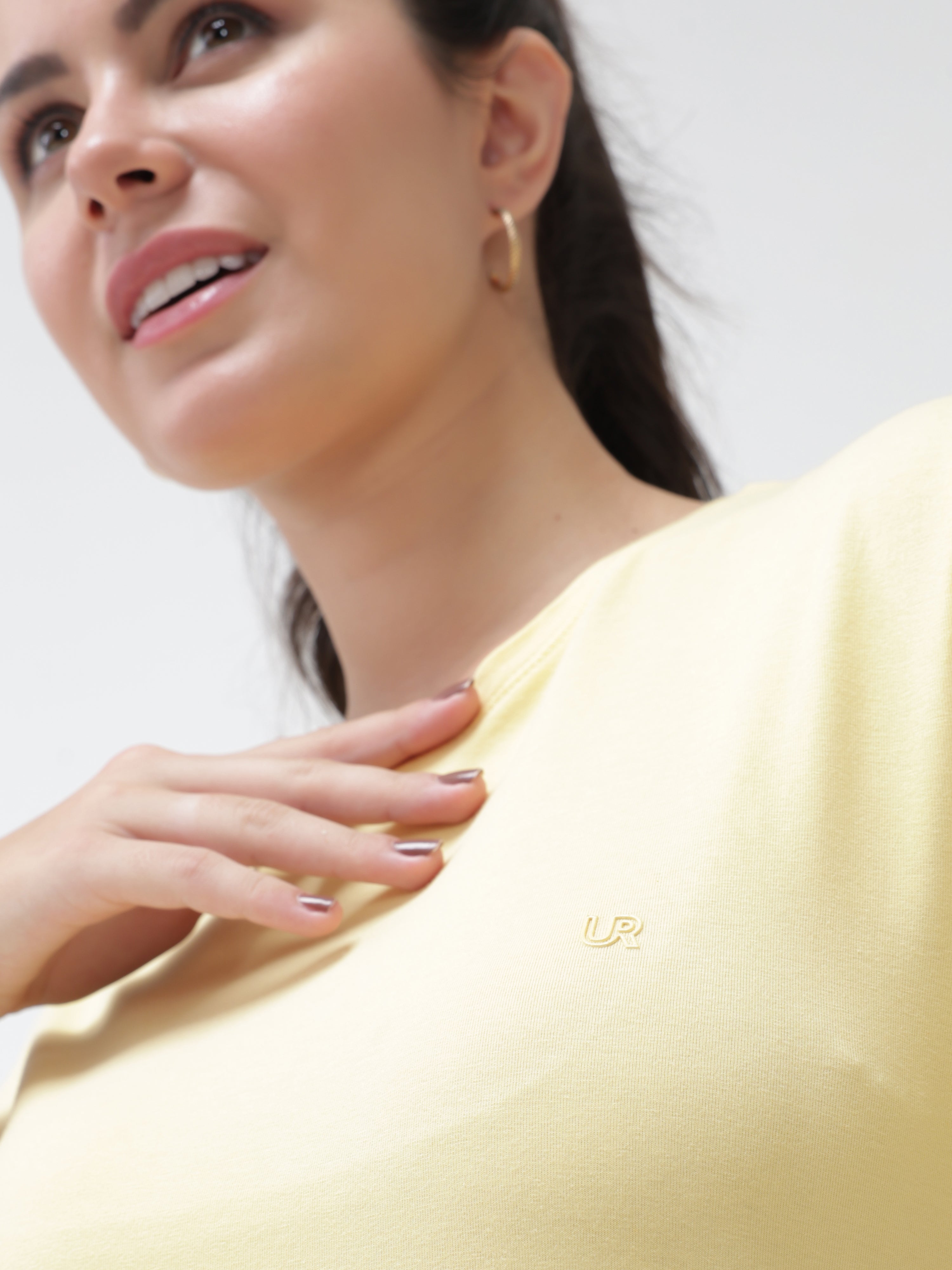 Woman wearing a stylish yellow round-neck T-shirt from Turms, showcasing comfortable and innovative fabric.