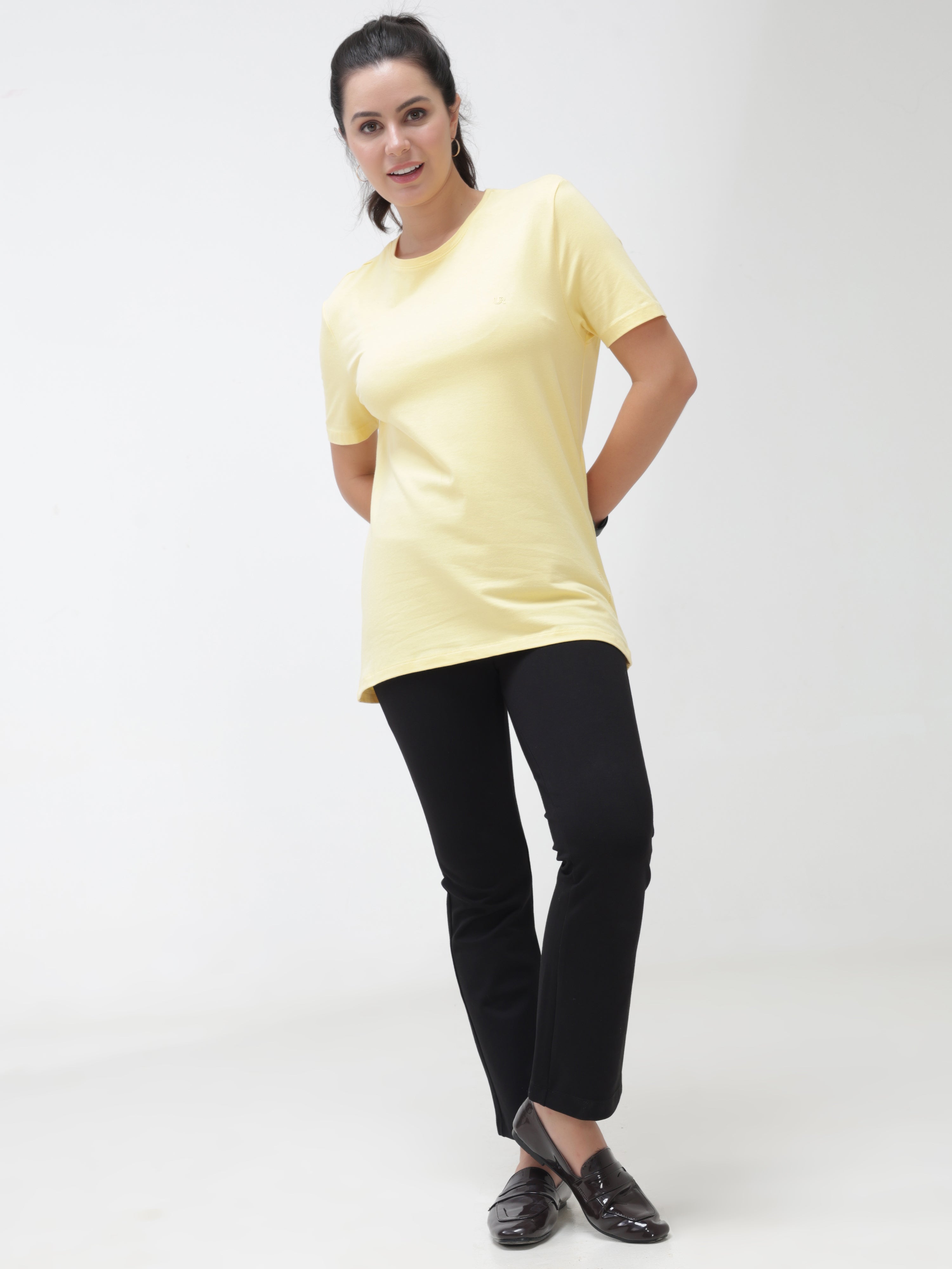 Woman wearing a yellow, round-neck T-shirt paired with black pants from Turms, showcasing trendy, stylish casual wear for women.