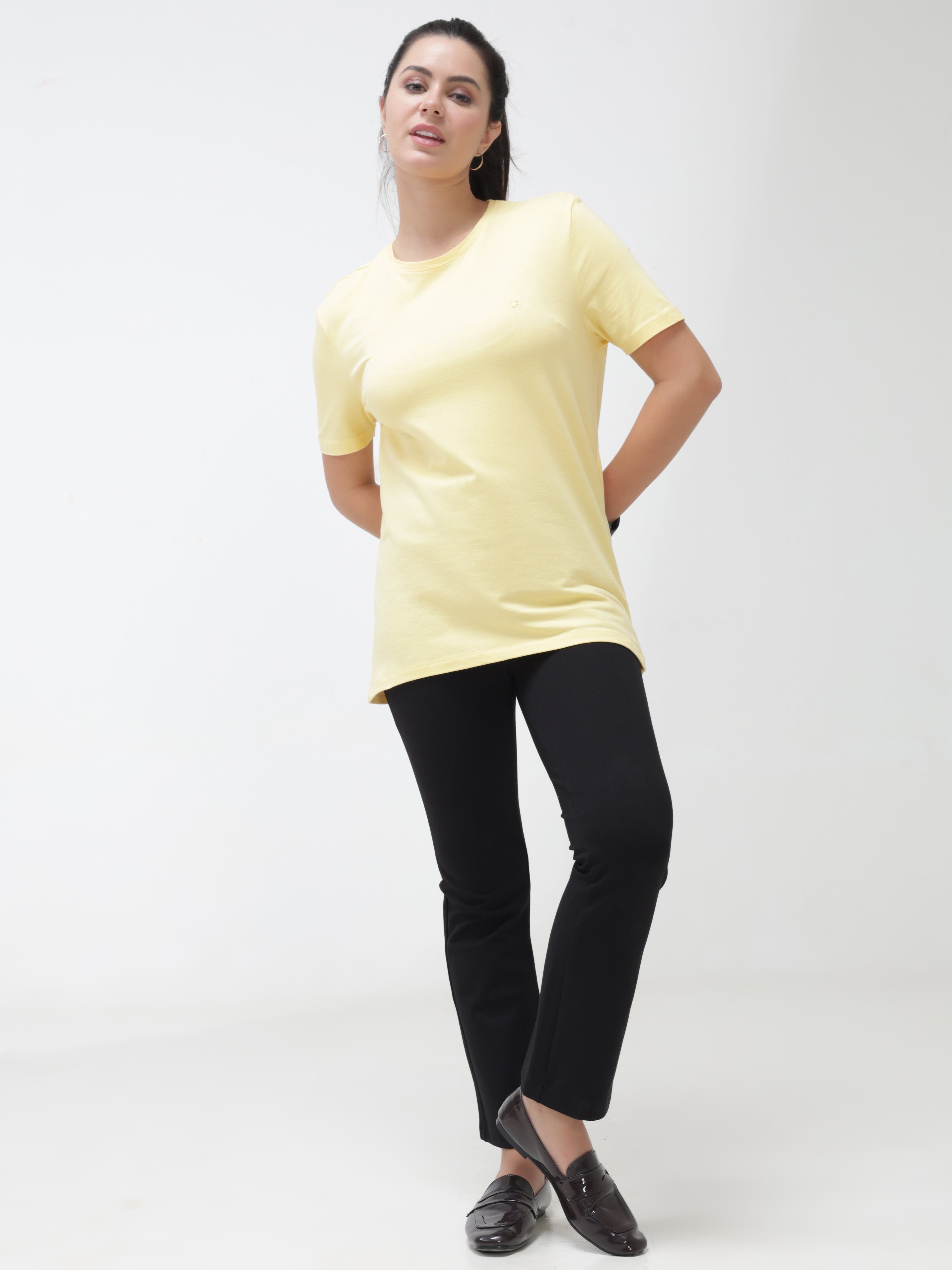 Woman wearing a stylish yellow round-neck t-shirt and black pants, showcasing casual wear for women
