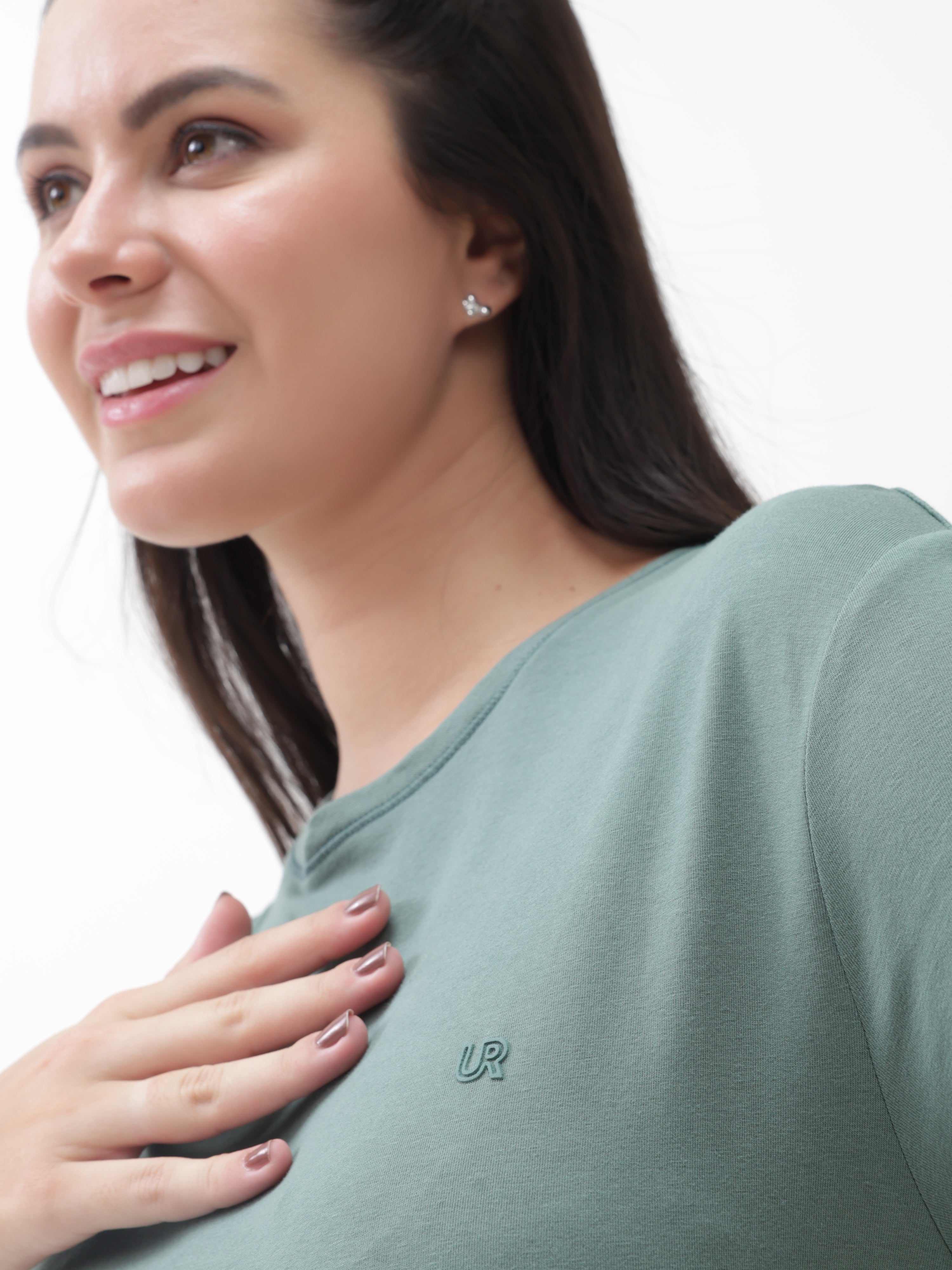 Woman wearing Simple Green Turms T-shirt with round neck and logo, showcasing tailored fit and stylish design against a white background.