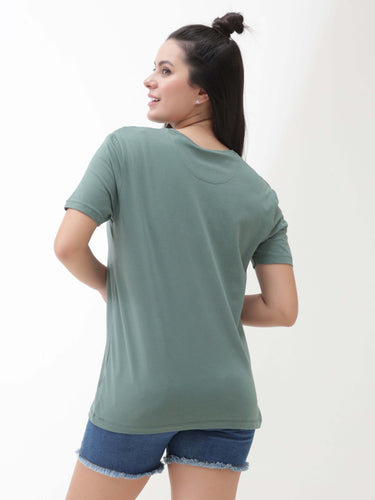 Woman wearing a Simple Green round-neck Turms T-shirt and blue shorts, showcasing the back view of the stain-proof and odor-resistant apparel.