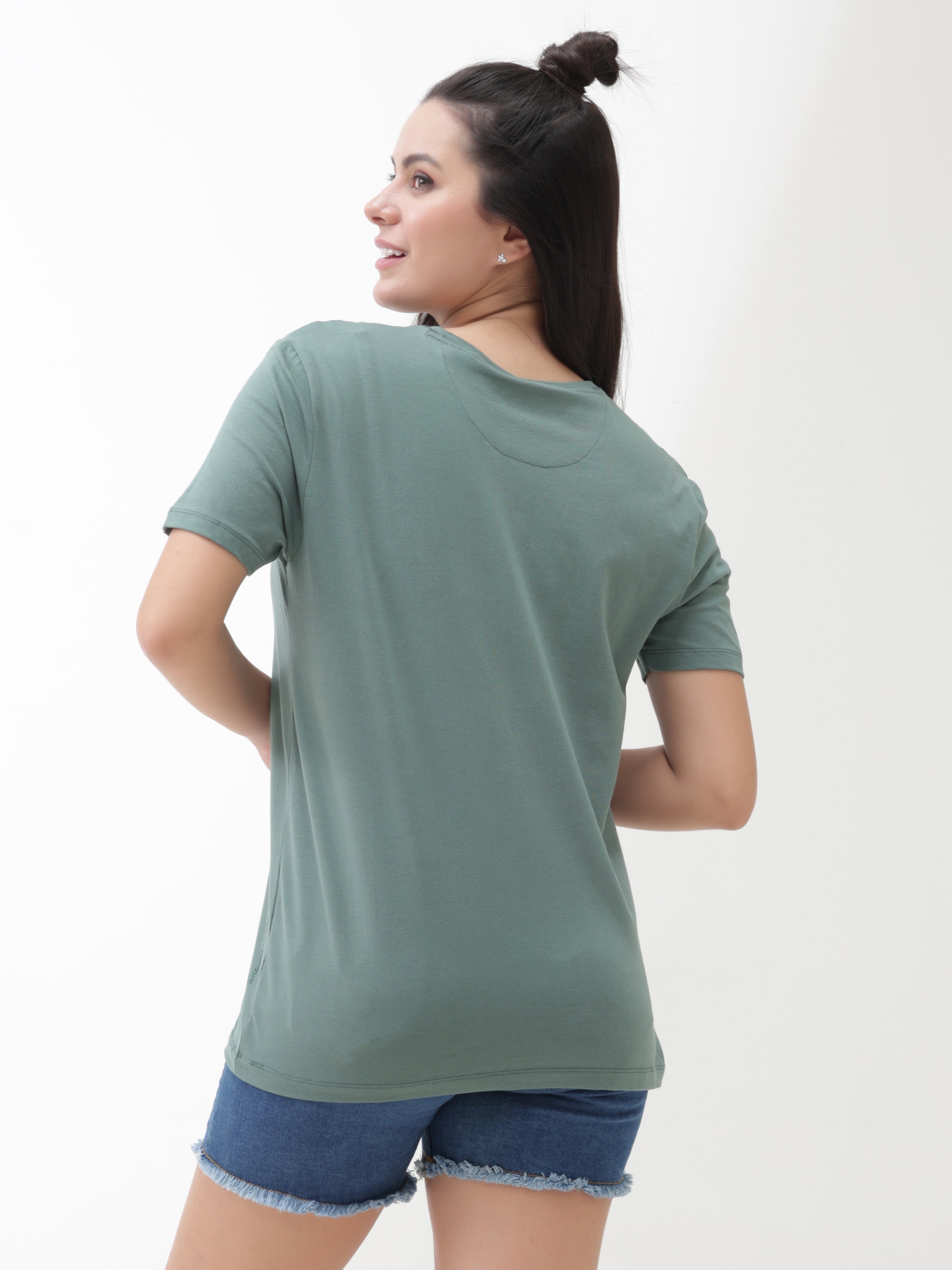 Woman wearing a Simple Green round-neck Turms T-shirt and blue shorts, showcasing the back view of the stain-proof and odor-resistant apparel.
