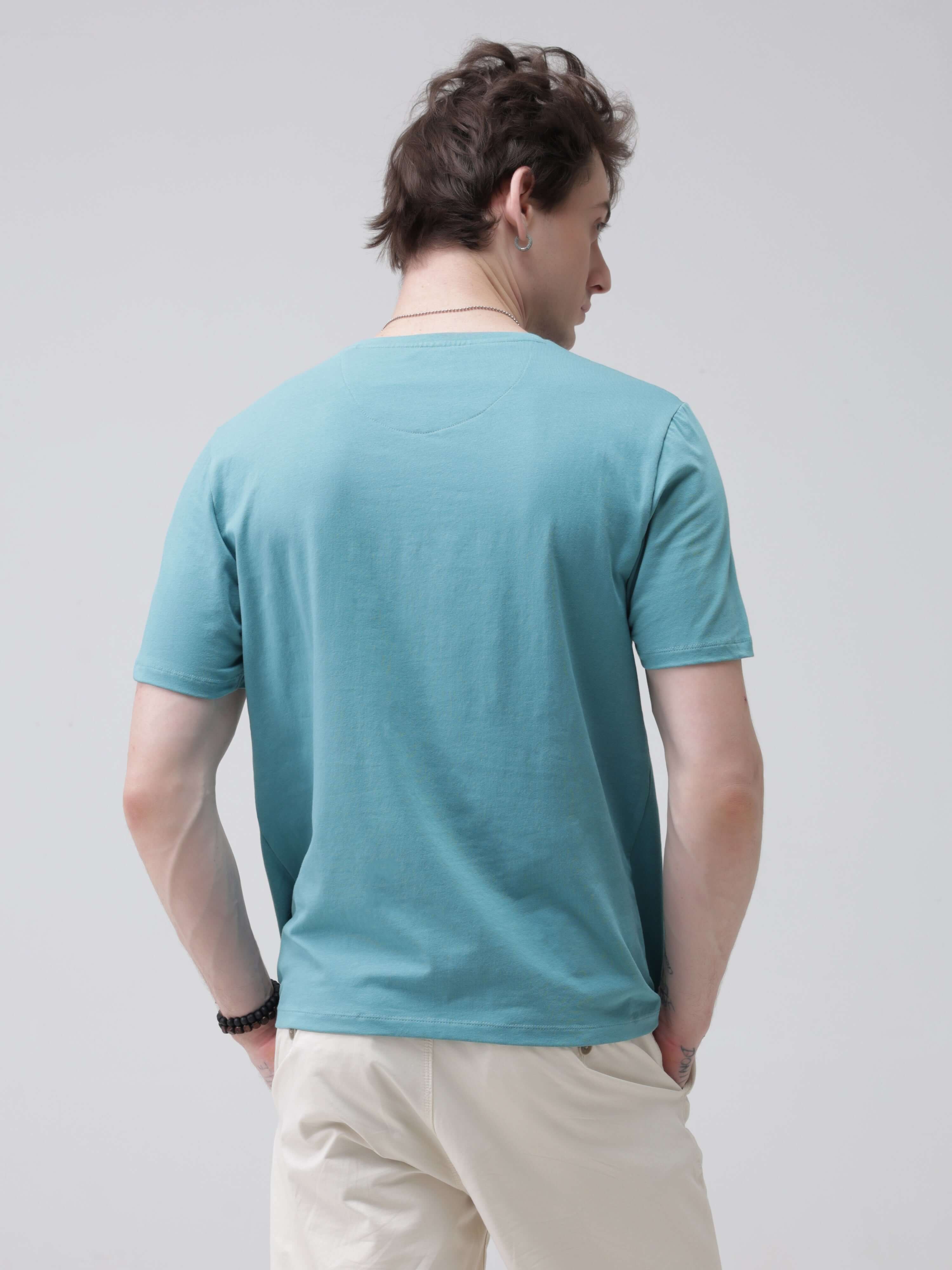 Man wearing turquoise round-neck Turms T-shirt, showcasing back view of water-resistant and anti-stain premium cotton menswear.