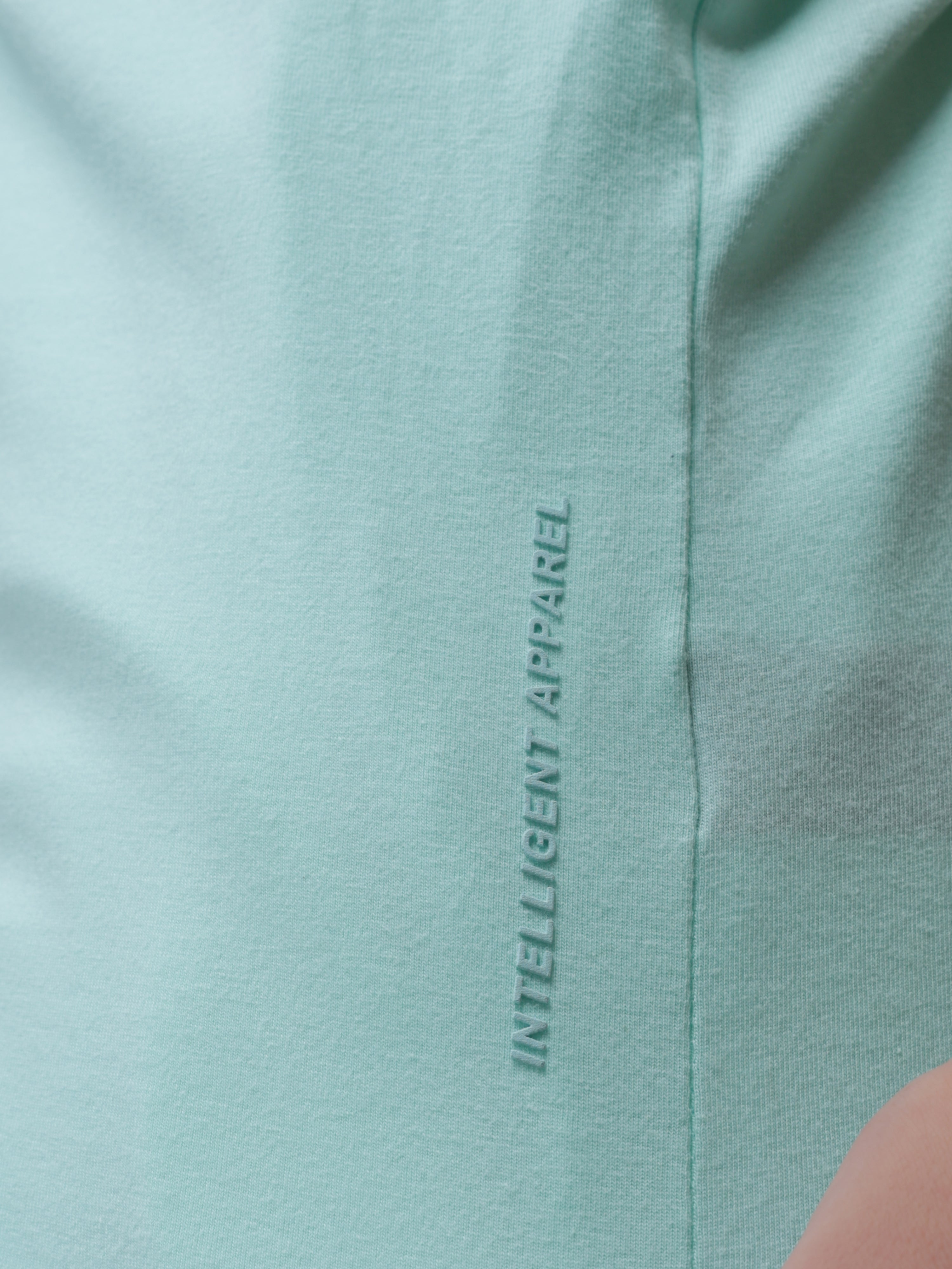 Close-up of Aqua Turms T-shirt showcasing text "INTELLIGENT APPAREL" on premium cotton fabric, highlighting advanced stain and odor-resistant technology.