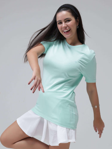 Woman smiling and wearing a light aqua round-neck t-shirt with white skirt, showcasing stylish casual wear.
