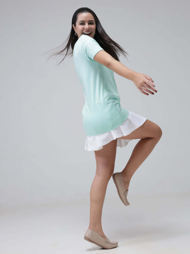 Woman in a stylish aqua round-neck T-shirt and white skirt, showcasing casual wear fashion, joyfully posing with a smile.