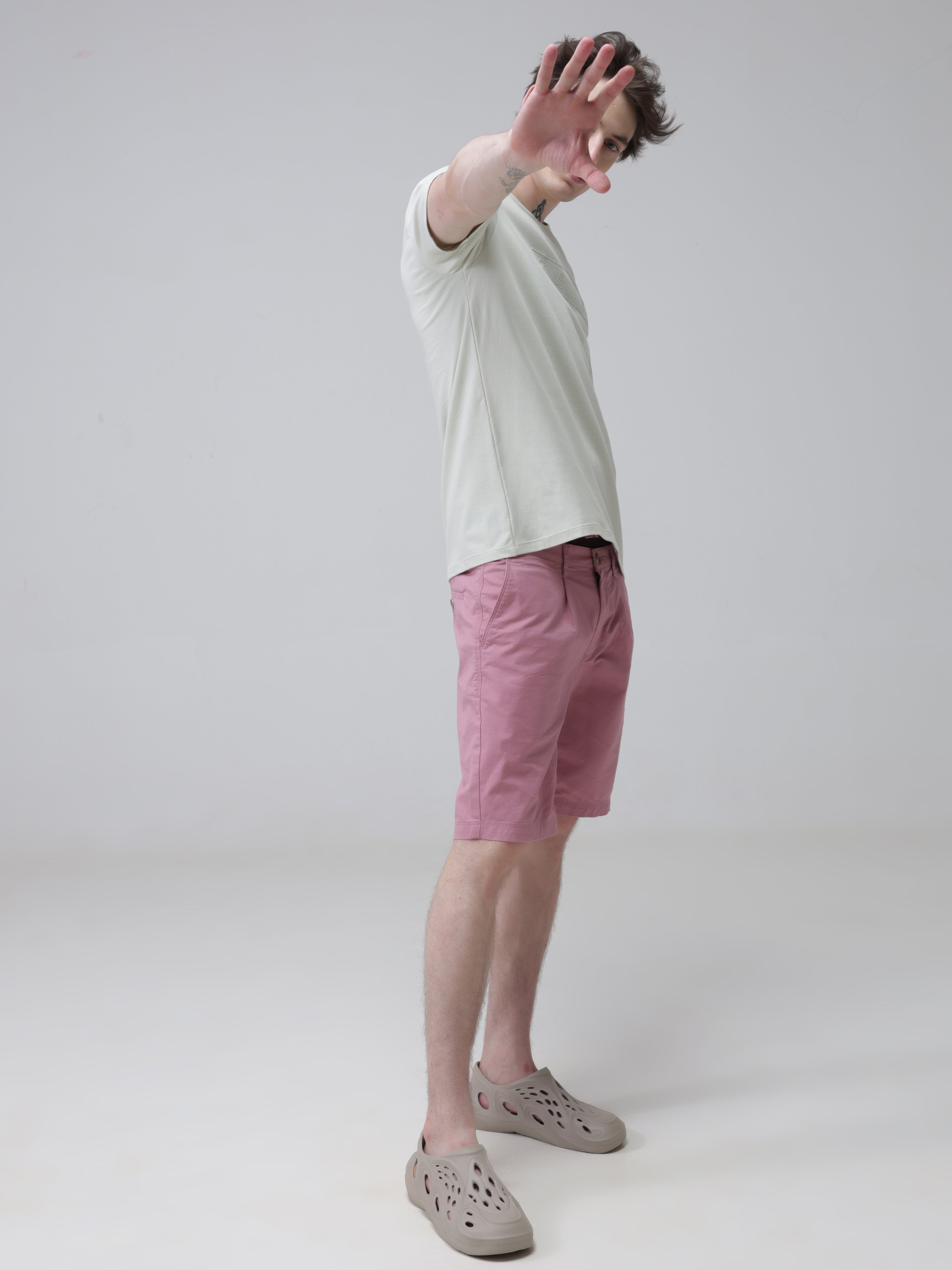 Man wearing Lime Enigma anti-stain and anti-odor Turms T-shirt with tailored fit and stretchable fabric, lifting hand, paired with pink shorts.