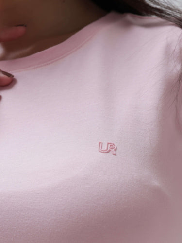 Close-up of a woman wearing a pink round-neck Turms T-shirt, displaying the anti-stain, anti-odour, and stretchable features of this intelligent apparel.