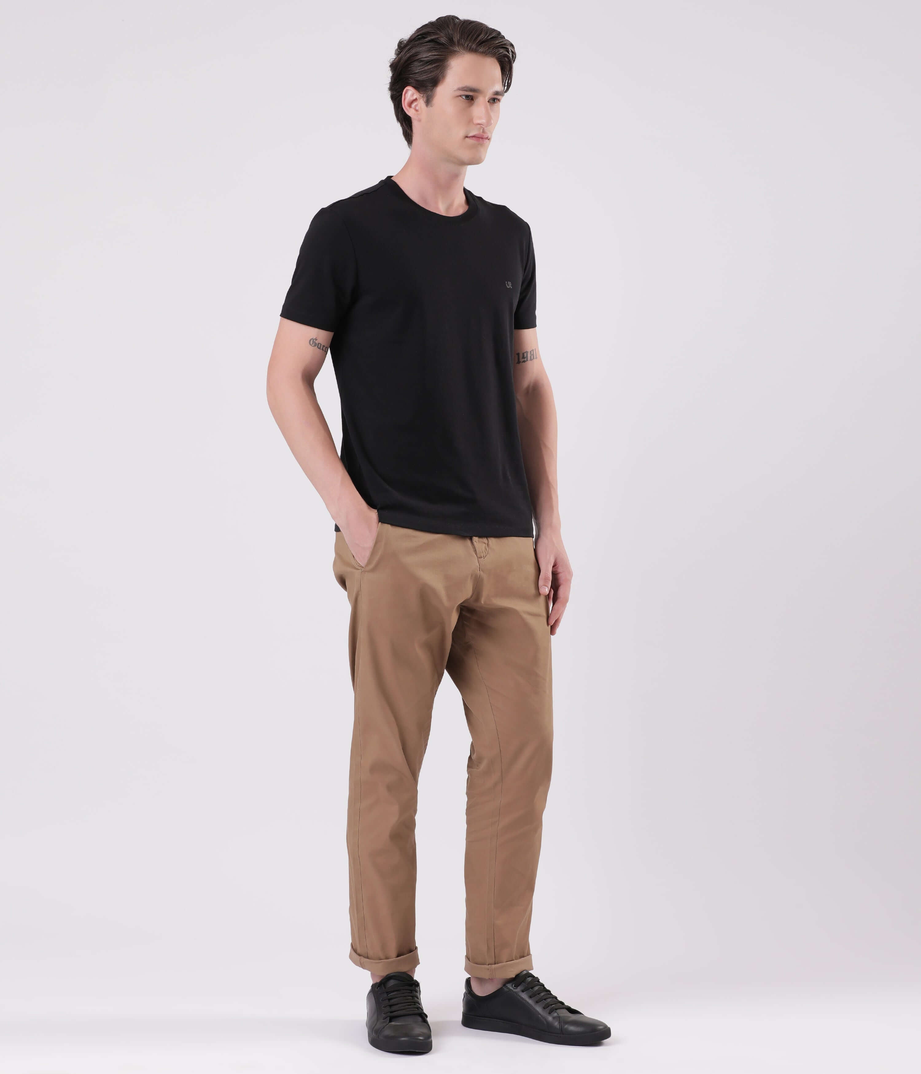 A model wearing Turms Dessert Mirage outfit featuring a black t-shirt and beige chinos for everyday luxury.