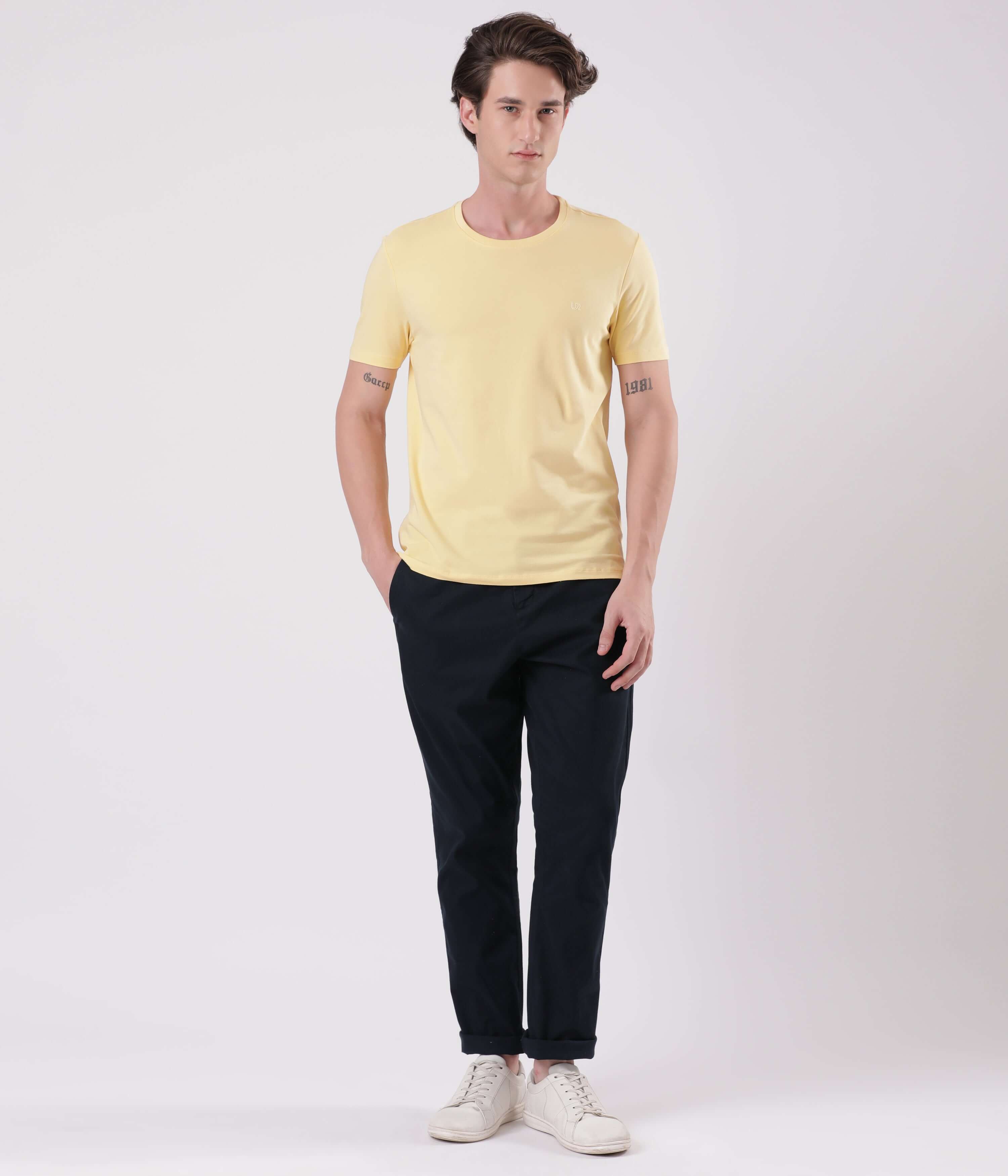 A model wearing a yellow t-shirt with navy chinos and white sneakers, showcasing casual style and comfort.