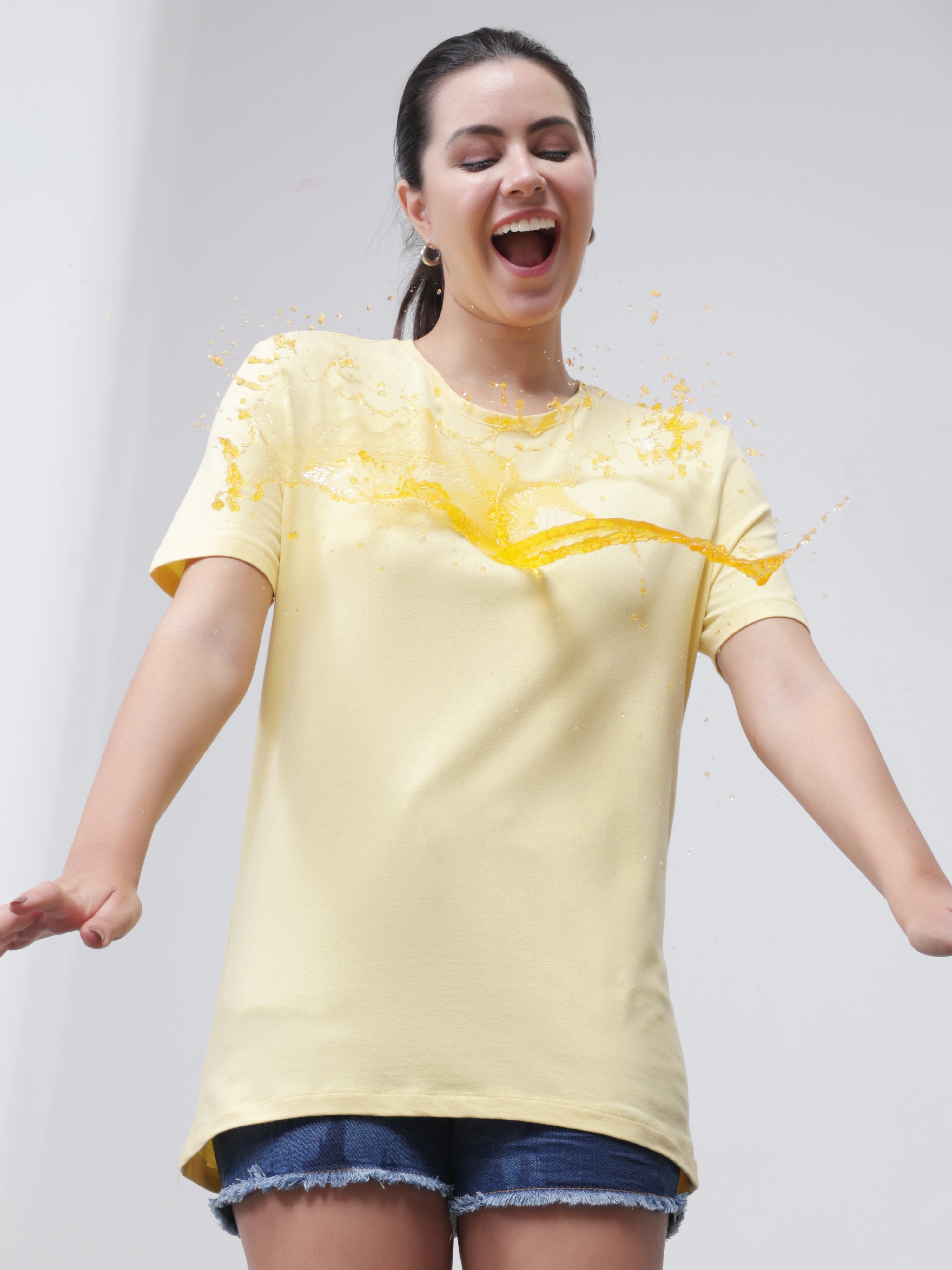Woman wearing stain-resistant round neck yellow Turms T-shirt, enjoying spill resistance, promoting stylish, premium cotton casual wear for men and women.