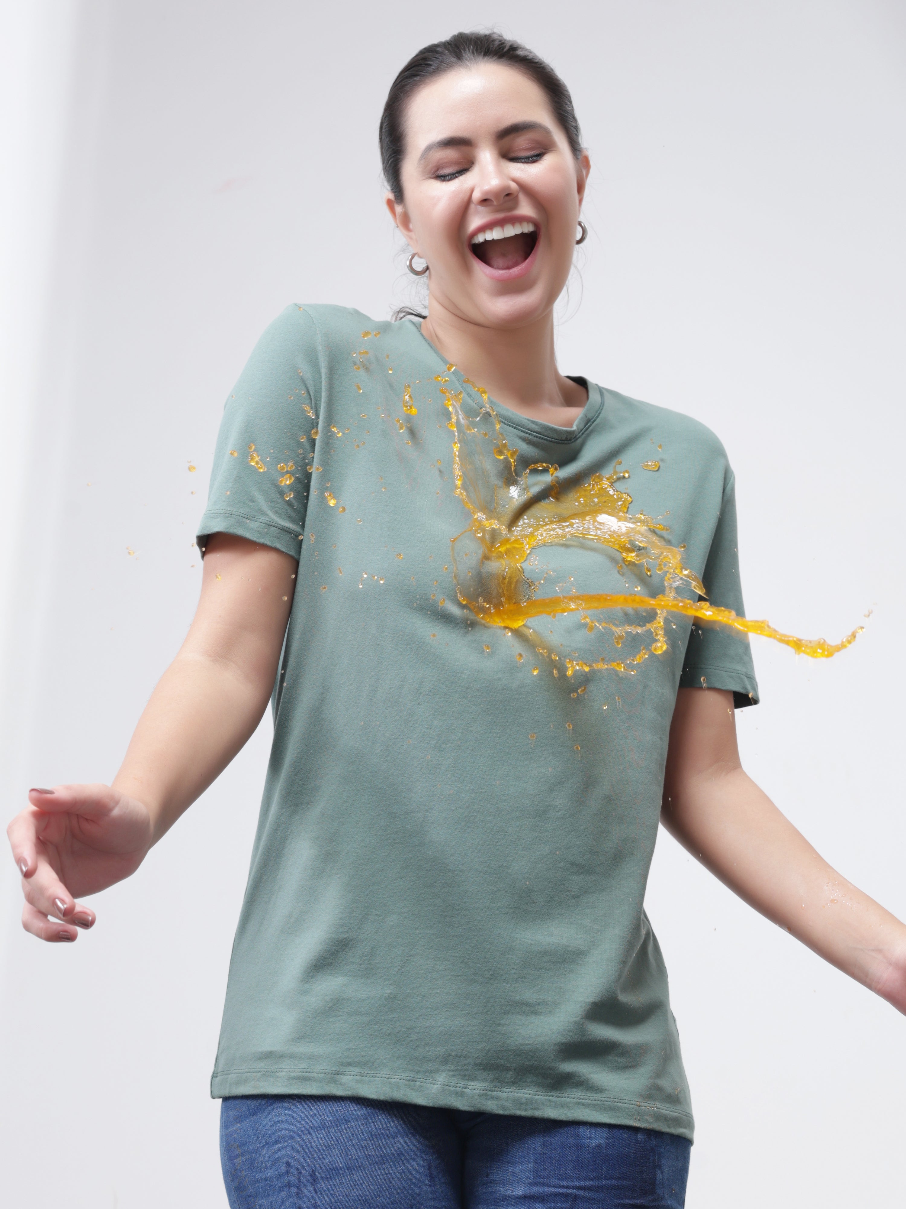 Woman smiling while liquid spills on her Simple Green stain-repellent and odor-resistant round-neck Turms T-shirt.