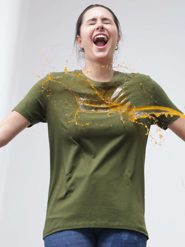 Woman wearing a green stain-proof and odor-resistant round-neck T-shirt while liquid spills off, showcasing stain-repellent quality