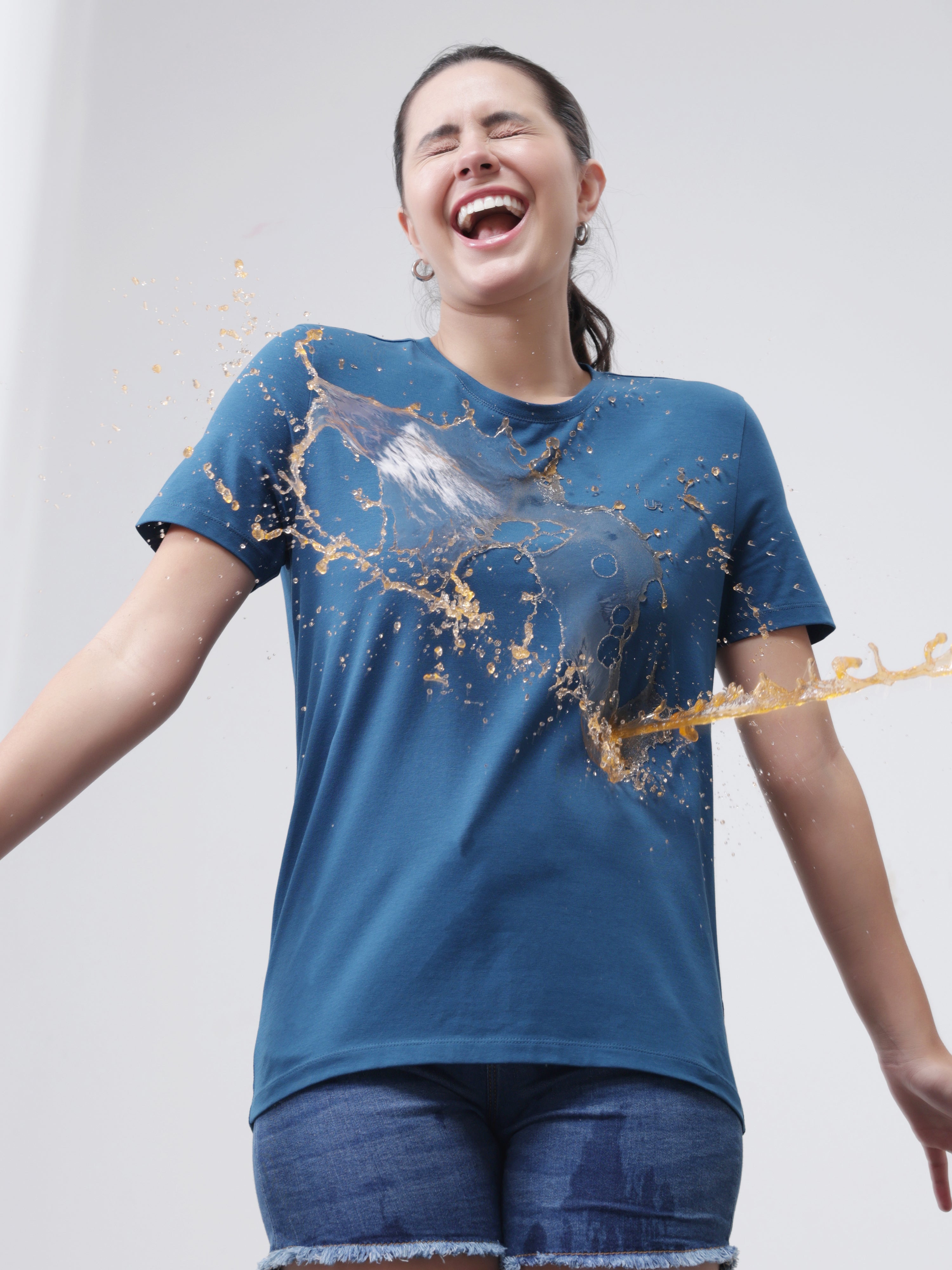 Woman wearing Sea Blue Turms T-shirt demonstrating stain-proof and anti-odor technology with liquid repelling off the fabric.