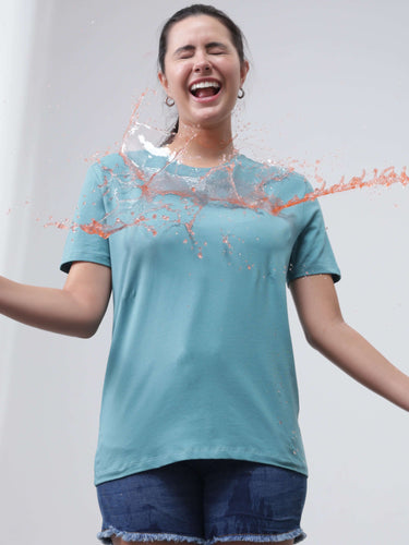 Woman wearing a water-resistant, stain-proof Turms T-shirt in blue, demonstrating its protection against spills.