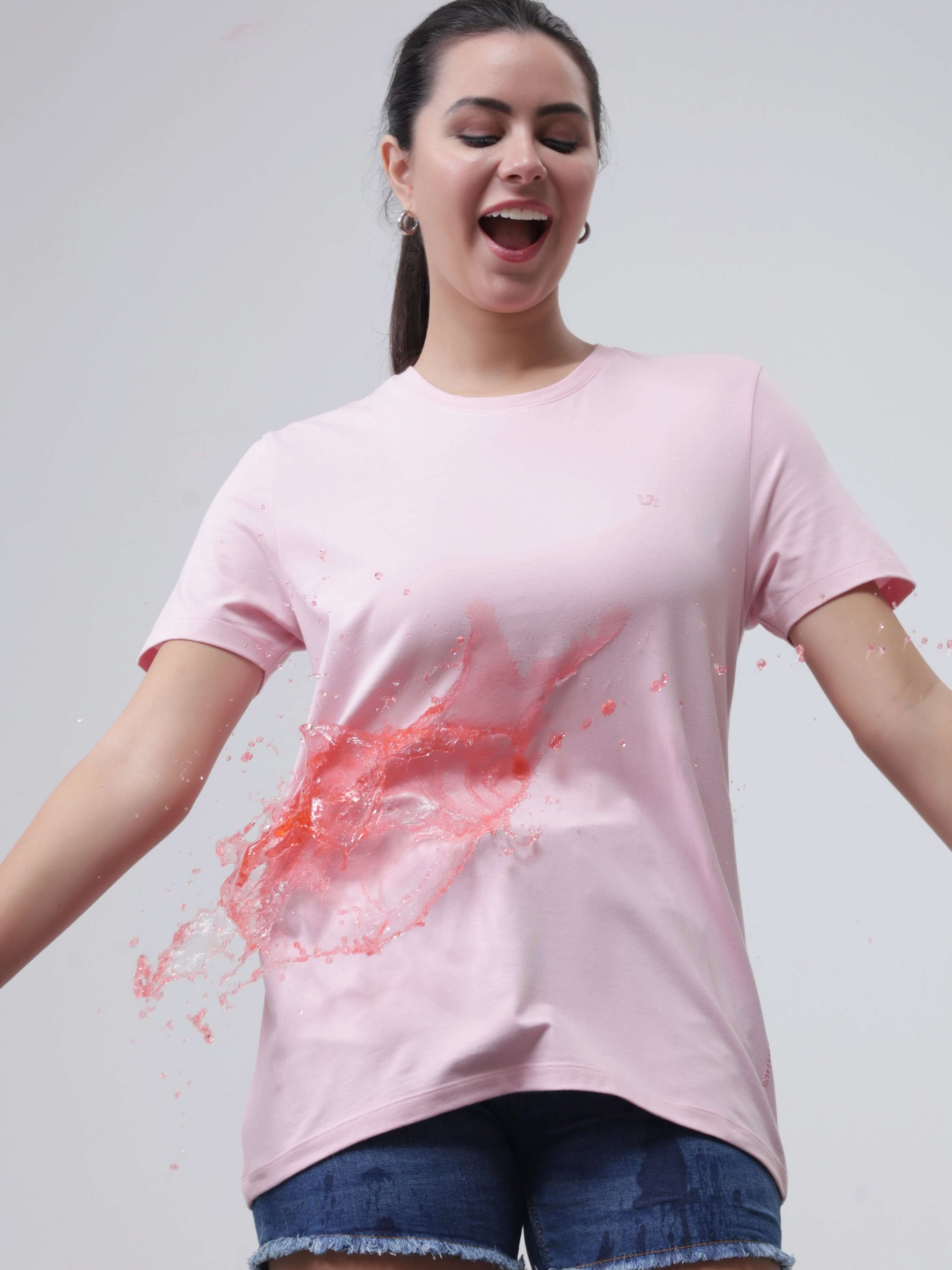 Woman wearing pink Turms Mystic Orchid T-shirt with stain-repellent and anti-odor technology, demonstrating spill resistance.