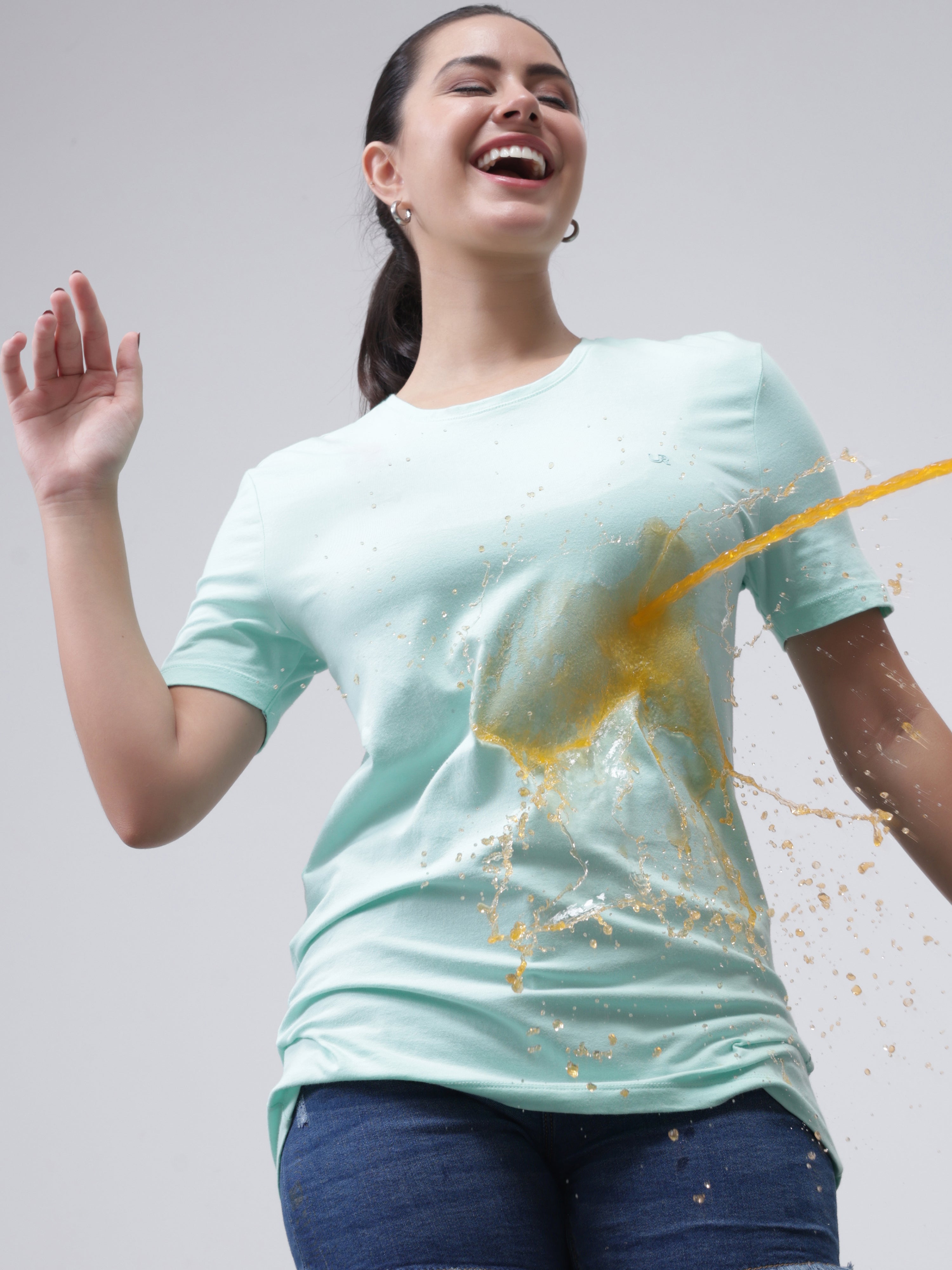 Woman wearing Aqua stain-proof and odor-resistant round-neck Turms T-shirt, demonstrating its stain-repellent quality against spills.