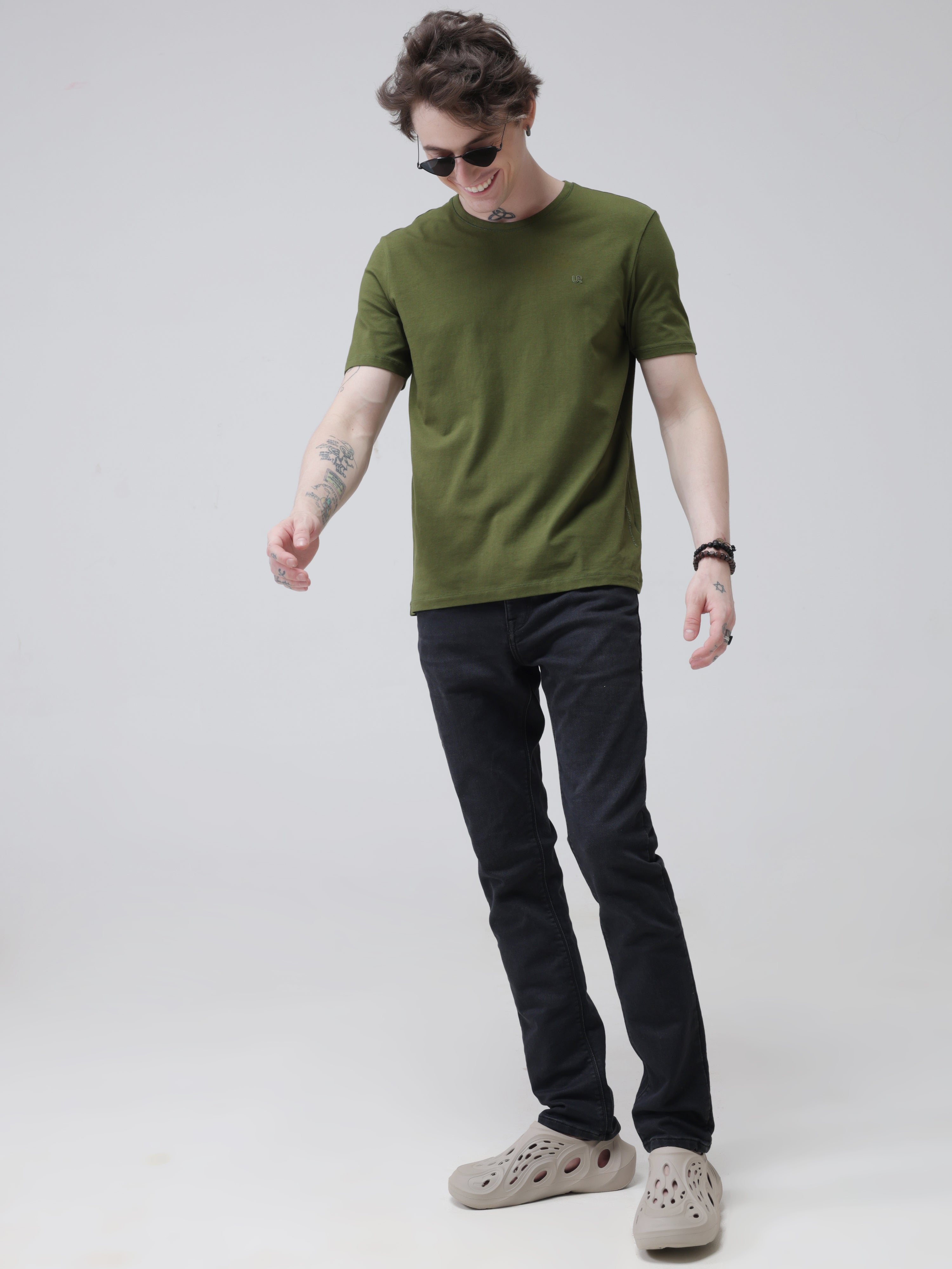 Man wearing green Turms round-neck t-shirt and black jeans, showcasing water-resistant and anti-stain menswear.