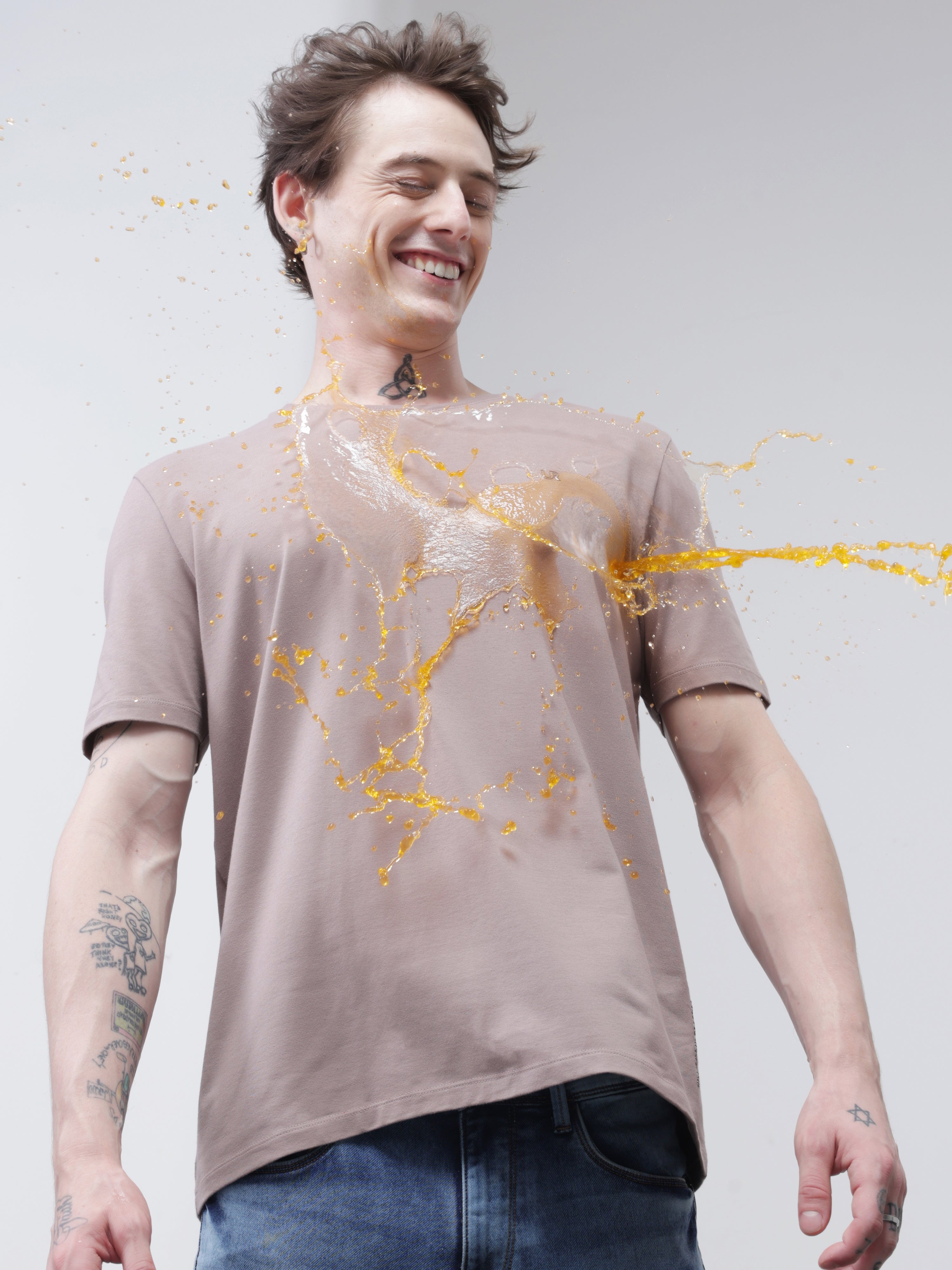 Man wearing a stain-proof Dusky Maroon Turms T-shirt, smiling as liquid spills on his shirt. Round neck, tailored fit, stylish and odor-resistant.