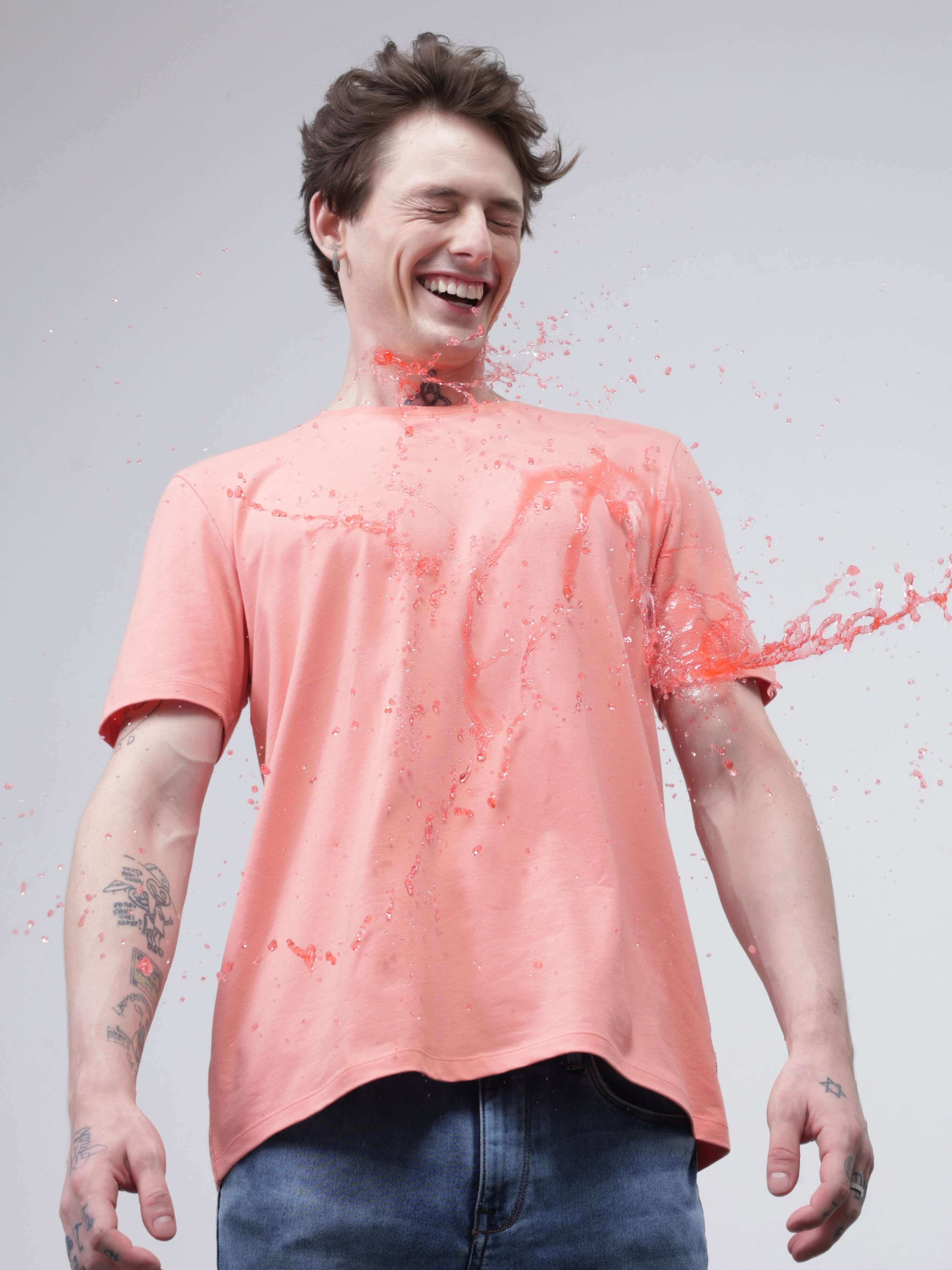 Man wearing Sunset Spice round-neck Turms T-shirt with stain-proof and anti-odour properties, laughing as liquid spills on the shirt.