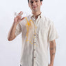 A man in a Sandy Glow linen shirt showcasing its anti-stain feature while spilling juice from a glass.