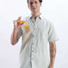 Model in Limey Cream linen shirt demonstrating anti-stain feature while holding a drink.