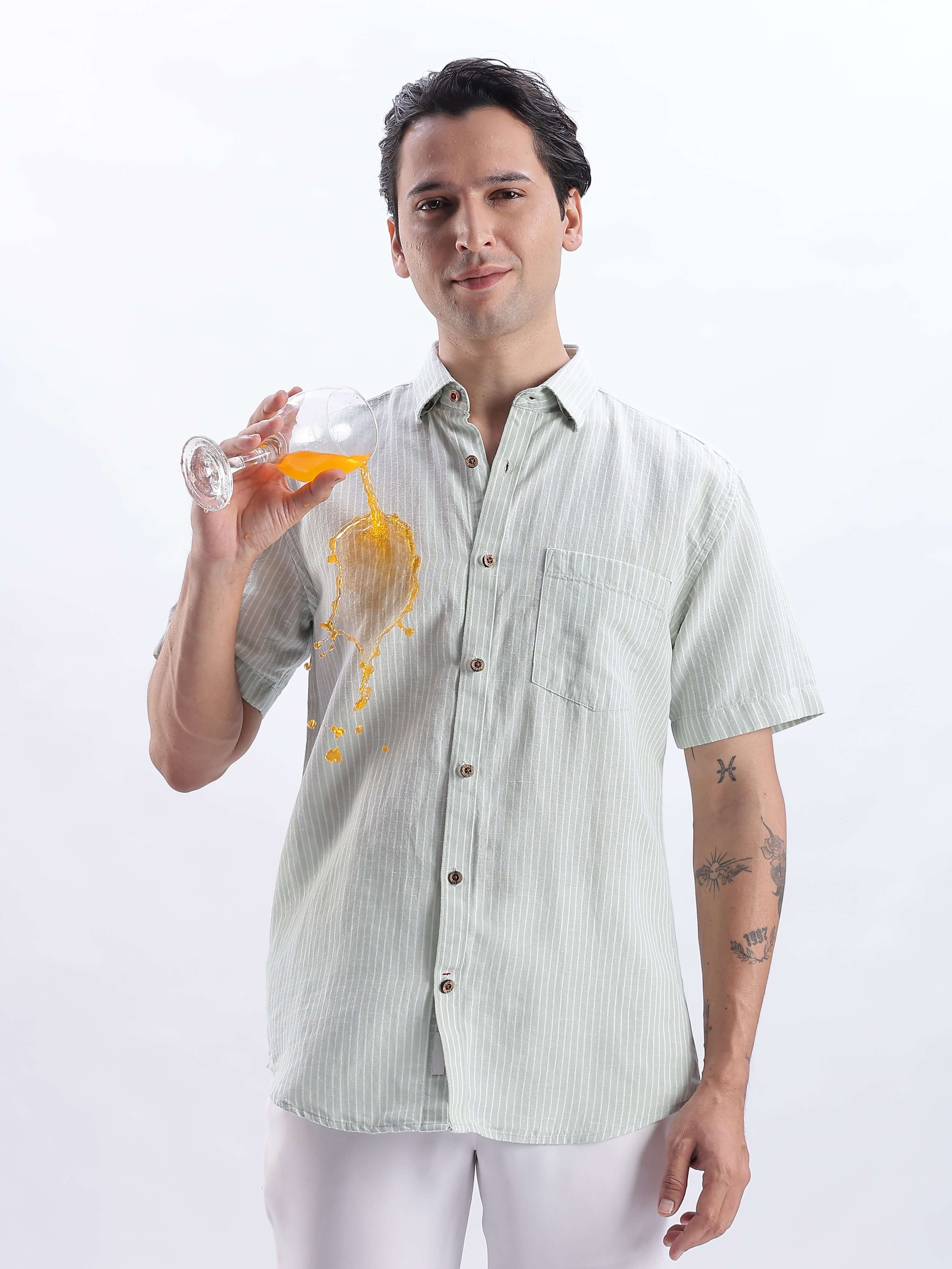 Model in Limey Cream linen shirt demonstrating anti-stain feature while holding a drink.