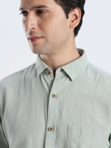 Man wearing a light green shirt with a plain background