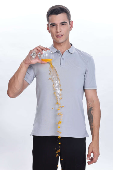 Magma Grey cotton polo tshirt being poured with orange liquid, showcasing its premium waterproof and antistain features.