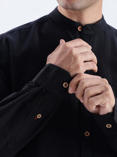 Close-up of hands modeling the Nocturne Black shirt, showcasing premium linen craftsmanship and button details.