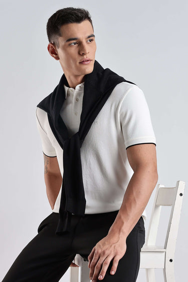 Model wearing White Owl cotton polo tshirt with a stylish black sweater draped over shoulders.