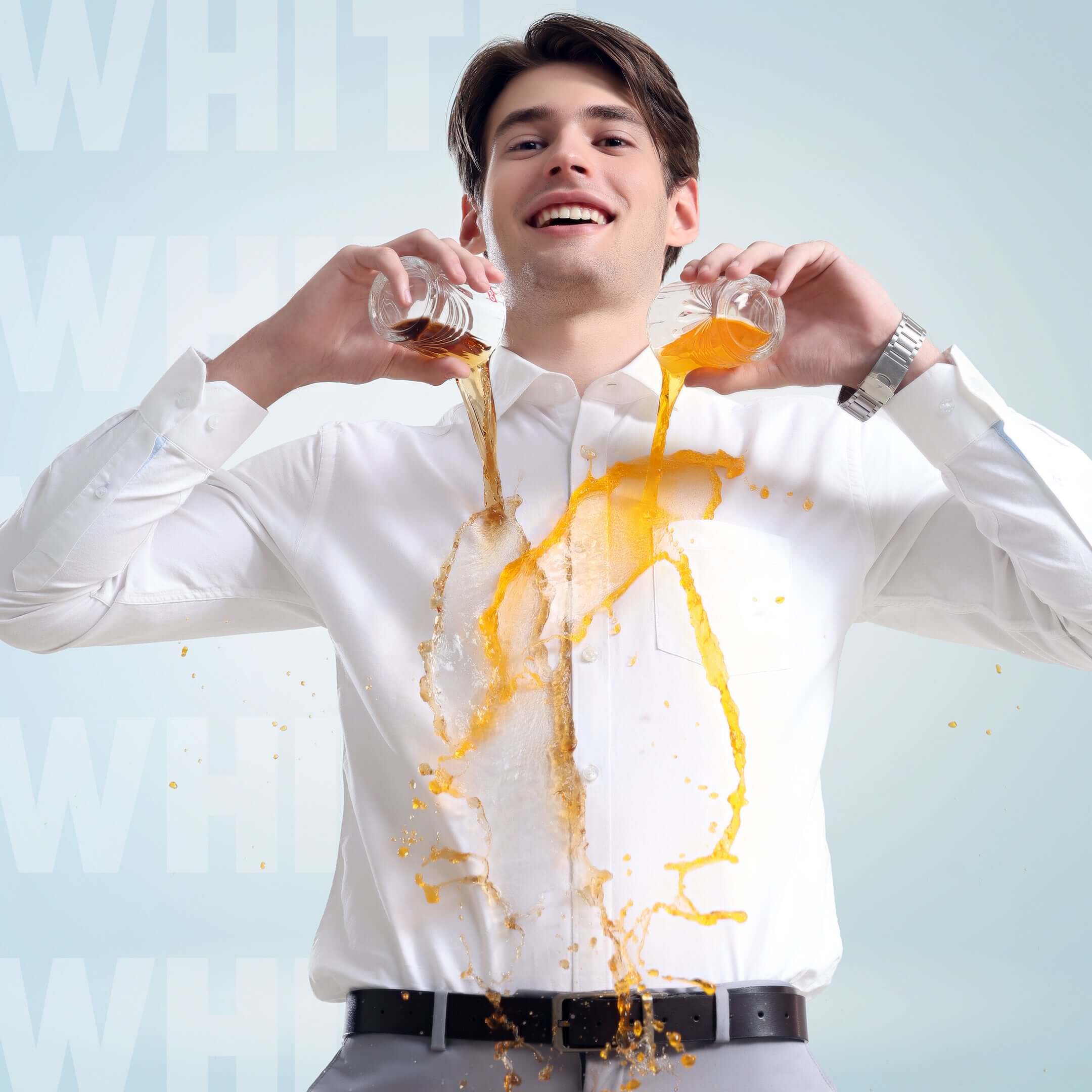 Man demonstrating anti-stain feature of Moonlite White Oxford Turms shirt with orange juice spill on premium cotton fabric.