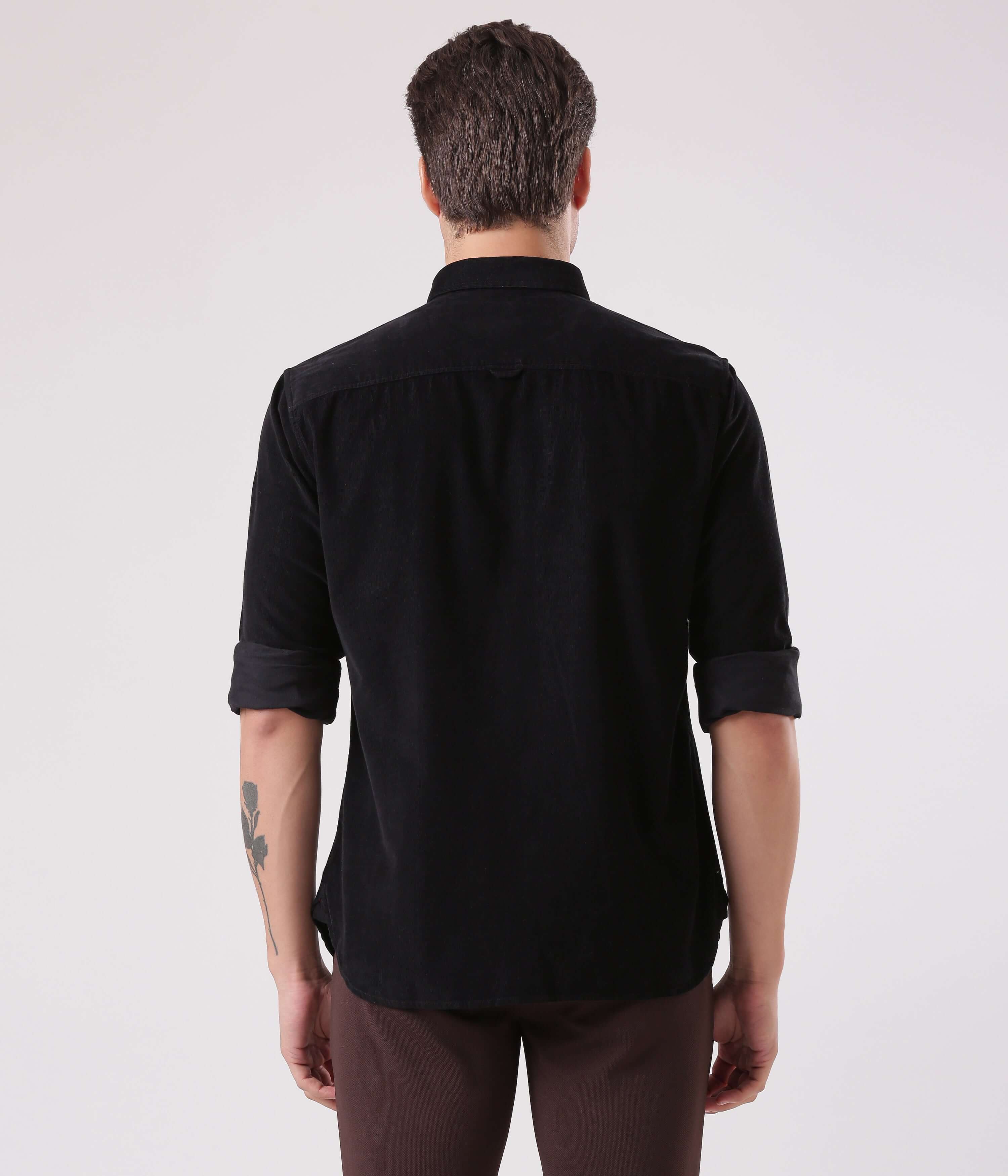 Back view of a man wearing the Black Beauty corduroy shirt, showcasing its sleek design and quality craftsmanship.