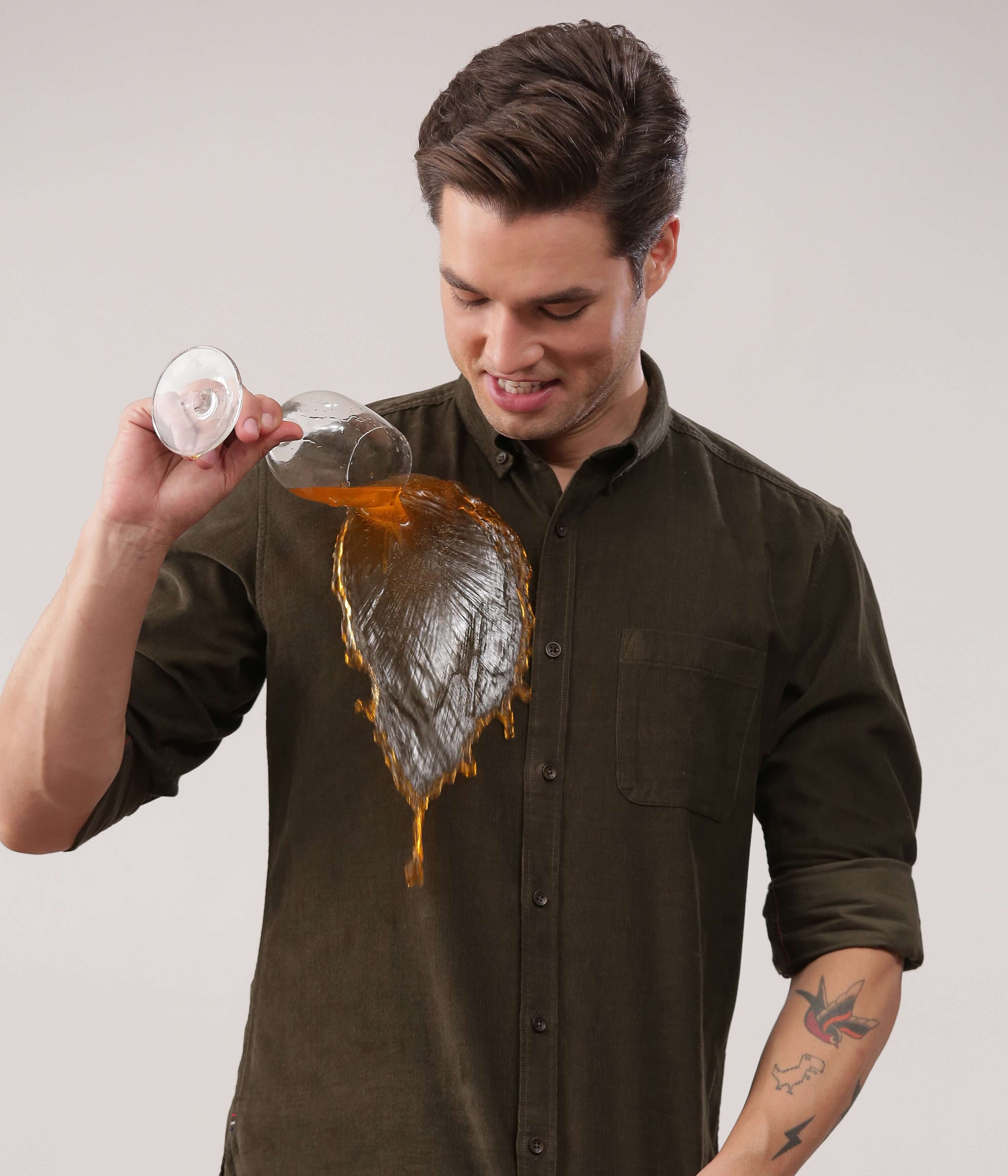 A model showcasing the Emerald Star corduroy shirt, demonstrating its waterproof feature by pouring liquid.