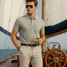 Stylish man wearing Magma Grey cotton polo tshirt on a yacht, enjoying a drink with a scenic ocean backdrop.