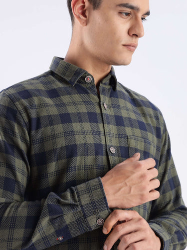 Man wearing a stylish olive and navy checked shirt made from recycled cotton, showcasing sustainable fashion.
