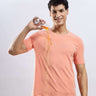Man wearing Ember Orange cotton tshirt, demonstrating its waterproof and anti-odour features with spilled drink.