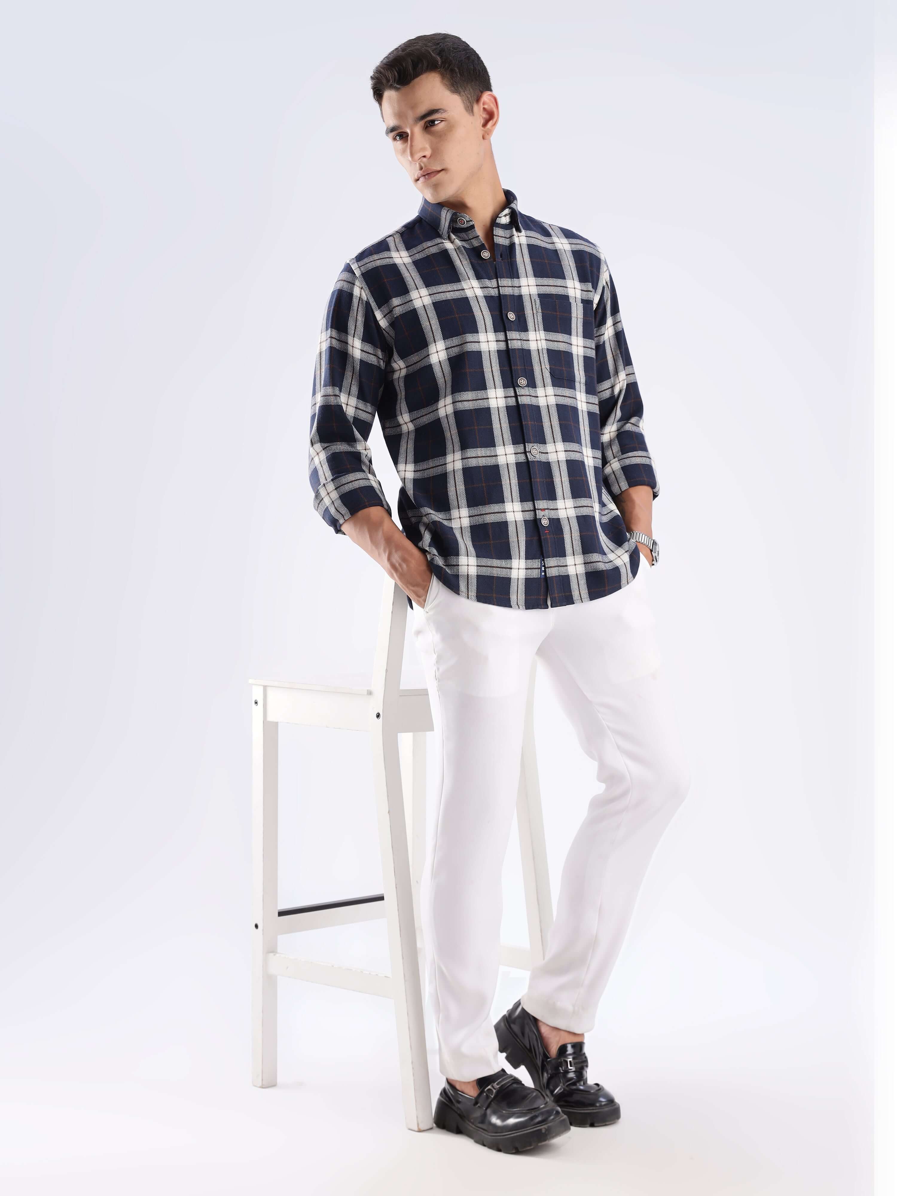 Stylish man wearing a blue checked recycled cotton shirt paired with white pants, showcasing sustainable fashion.