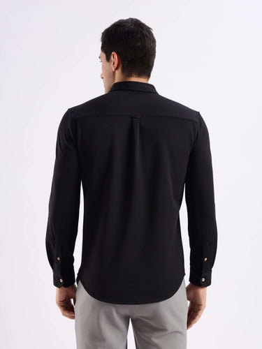Man wearing the Venice Black knitted shirt from Turms, showcasing 8-way stretch, anti-odour, and anti-stain features.