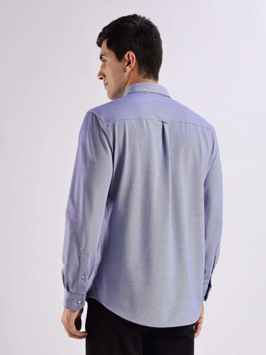 Back view of a man wearing a blue Turms knitted shirt, showcasing 8-way stretch and anti-odour technology.