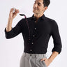 Man in a black Turms knitted shirt enjoying wine, showcasing premium anti-odour, temperature control features.