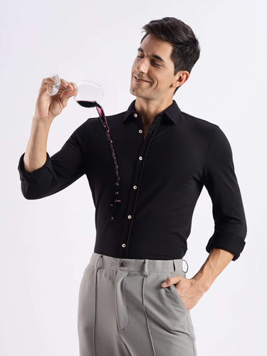 Man in a black Turms knitted shirt enjoying wine, showcasing premium anti-odour, temperature control features.