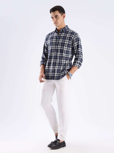 Man wearing a stylish checked recycled cotton shirt with white pants, showcasing sustainable fashion by Turms.