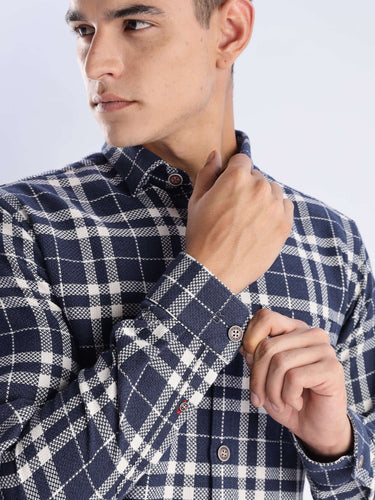 Stylish man wearing a navy and white checked recycled cotton shirt, showcasing its durable fabric and intricate stitching details.