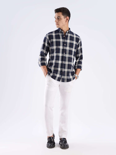 Man wearing a sustainable blue plaid recycled cotton shirt, paired with white pants and stylish black shoes.